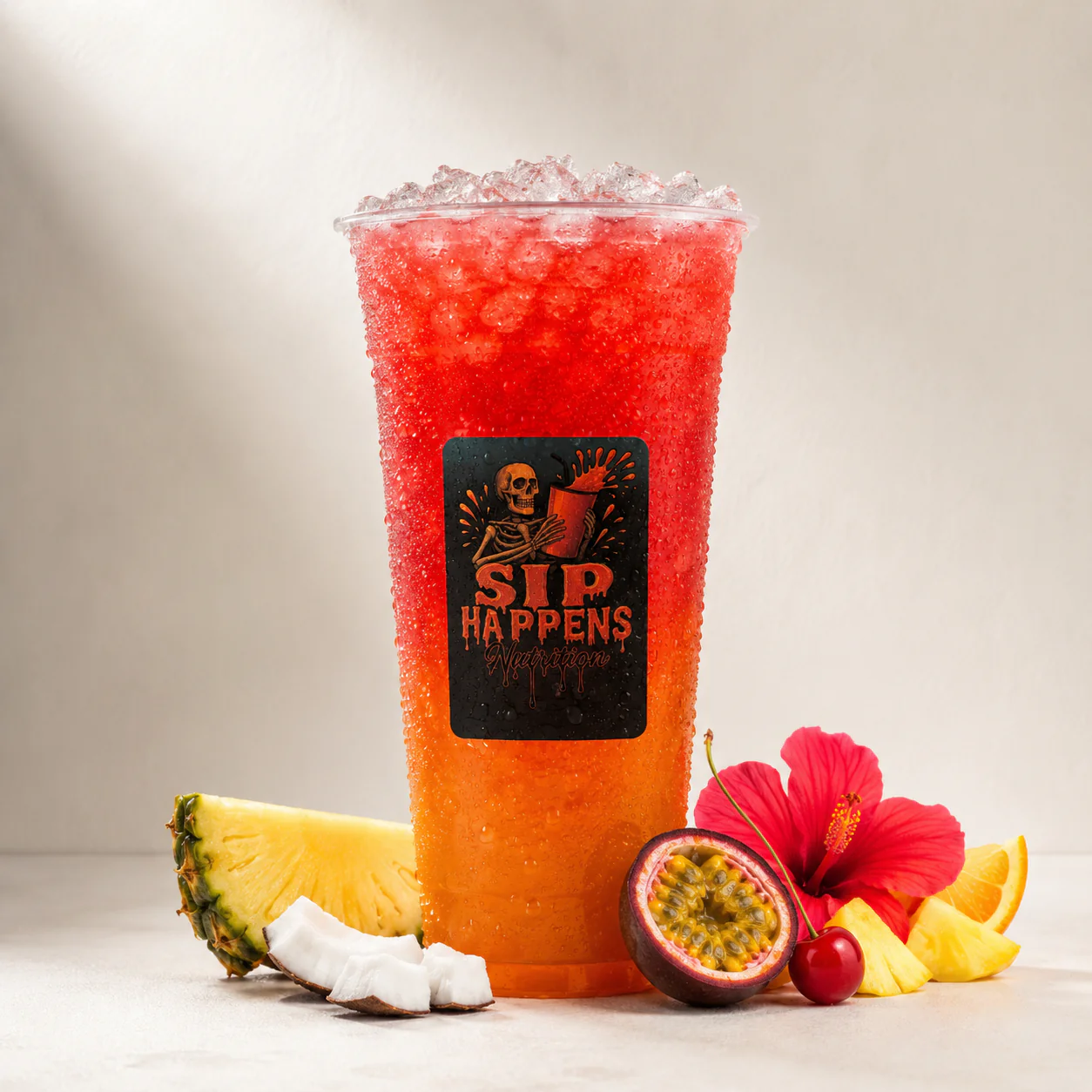 Sip Happens Nutrition iced drink with a red-to-orange gradient, surrounded by pineapple, coconut, passion fruit, cherry, and hibiscus flower