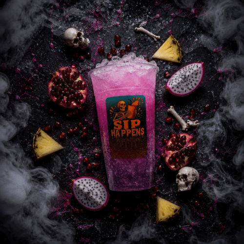 Sip Happens Nutrition branded cup filled with a purple iced drink, surrounded by pomegranate, dragon fruit, pineapple, and Halloween skull props with dramatic smoke effects