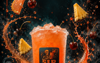 Sip Happens Nutrition orange fruit drink with crushed ice, surrounded by splashing juice, cherries, pineapple, orange, and coconut on a dark, spooky background