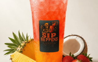 Sip Happens Nutrition iced drink with orange-to-red gradient, surrounded by pineapple, strawberries, and coconut