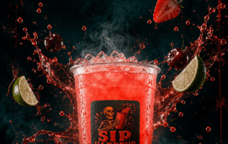 Sip Happens Nutrition red iced drink surrounded by splashing liquid, strawberries, cherries, and lime wedges on a dark, dramatic background