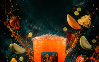 Sip Happens water bar branded cup with a layered orange-to-yellow frozen drink, surrounded by flying tropical fruits and dramatic splashes